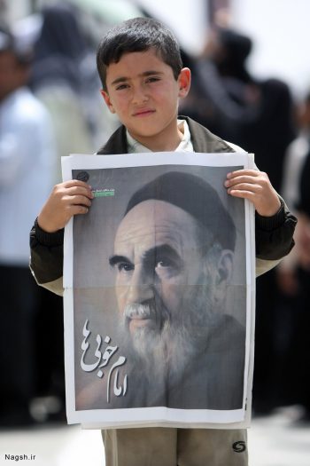 پوستر امام در دست پسر نوجوان